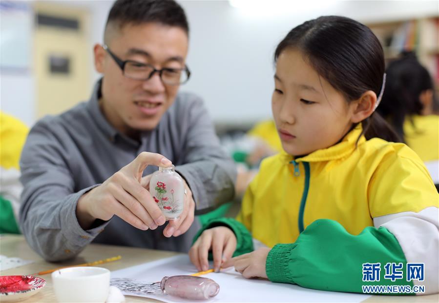 1月18日，衡水内画艺术博物馆的老师（左）为学生讲解鼻烟壶内画知识。 近年来，河北省衡水市珍宝街小学将当地的国家级非物质文化遗产项目衡水内画引入校园，开设校本课程，并成立“内画工艺坊”兴趣社团，在丰富校园文化生活的同时，让学生们近距离感受非遗的魅力，弘扬和传承传统文化。  新华社记者 朱旭东 摄