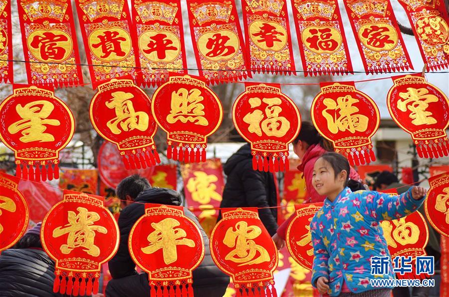 1月29日，一名小朋友在山东省淄博市沂源县东里镇年货大集的年货摊前玩耍。 春节临近，各地一片红火迎新春的浓浓年味。 新华社发（赵东山 摄）