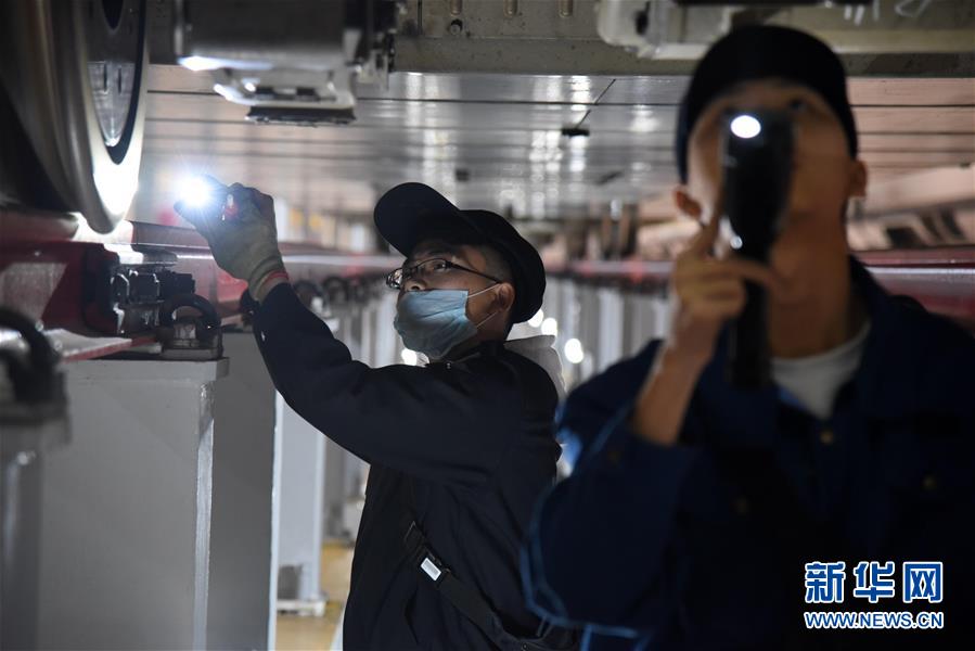 2月12日晚，济南东动车所的检修机械师在对一列复兴号进行检查。新华社记者王凯摄