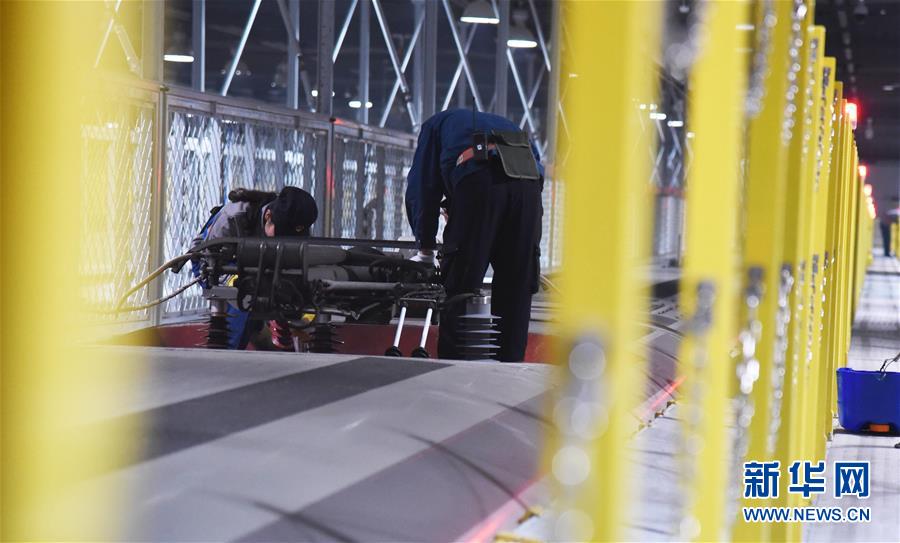2月12日晚，济南东动车所的检修机械师在检查一列复兴号的车顶设备。新华社记者王凯摄