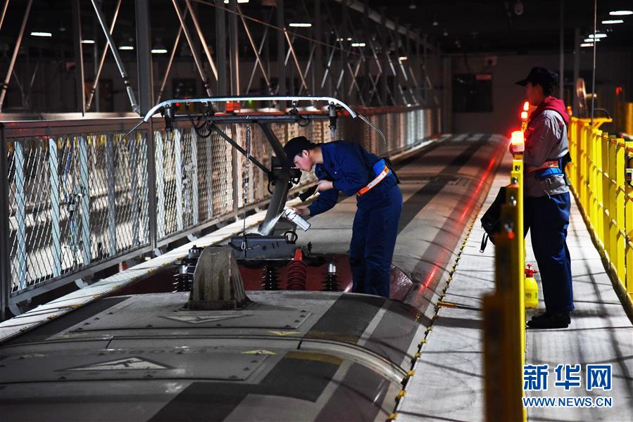 2月12日晚，济南东动车所的检修机械师在维护一列复兴号的车顶设备。新华社记者王凯摄
