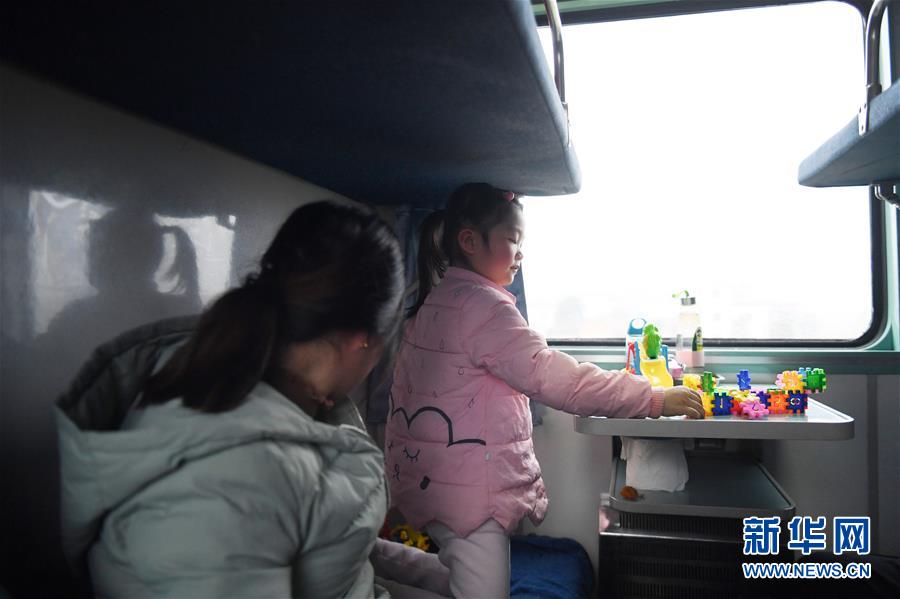 2月12日，在由合肥开往广州的T3089次临客列车上，来自安徽涡阳县的汪韵雅（右）在玩玩具。父母带着她前往广州打工。
