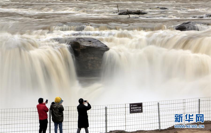 3月3日，游客在黄河壶口瀑布景区游览拍照。近日，随着气温回暖，受上游融冰开河速度加快影响，黄河壶口瀑布水量增大，气势磅礴。 新华社发（王辉耀 摄）