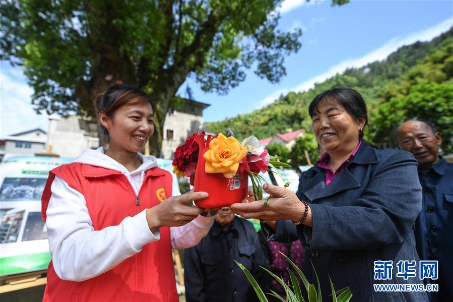 5月7日，湍口镇迎丰村的党员志愿者胡丽娟（左）在“乡村流动课堂”上给村民展示一个用废弃塑料瓶做成的插花盆。 浙江省杭州市临安区湍口镇是浙西的旅游小镇。近年来，湍口镇在发展乡村全域旅游、提升乡村环境的过程中，组建了一支以基层青年党员为主的“乡村流动课堂”服务队，用通俗易懂的宣讲方式，提升乡村百姓的环保意识、旅游服务意识等，共建美好家园，助力乡村振兴和乡村旅游。 新华社记者 徐昱 摄