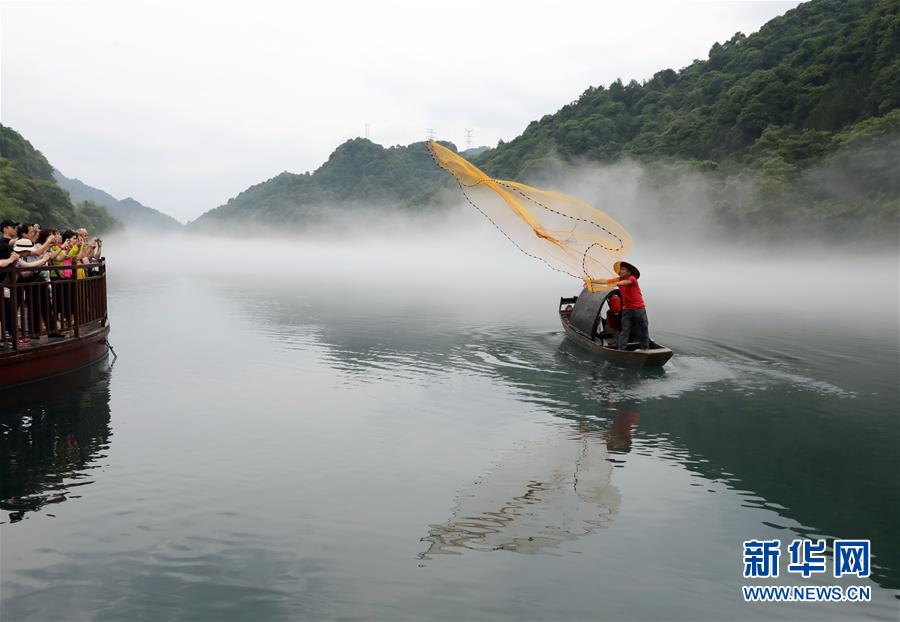 5月25日清晨，渔夫划着小船在小东江上撒网，吸引游人驻足。