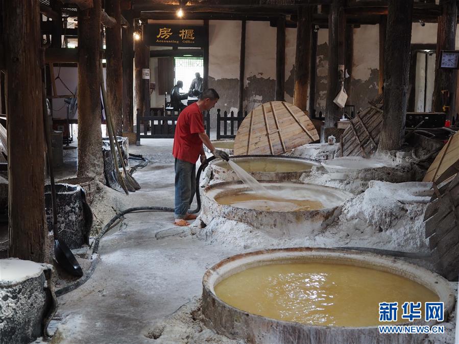 在凿成于1835年的燊海井，一名工人正从导管注入取自地下千米深处的盐卤，这是传统平锅煮盐方法的一个环节。