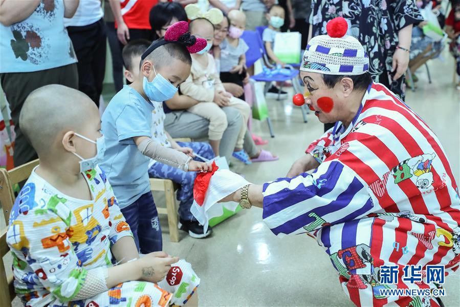 5月30日，志愿者“小丑叔叔”与白血病患儿做游戏。