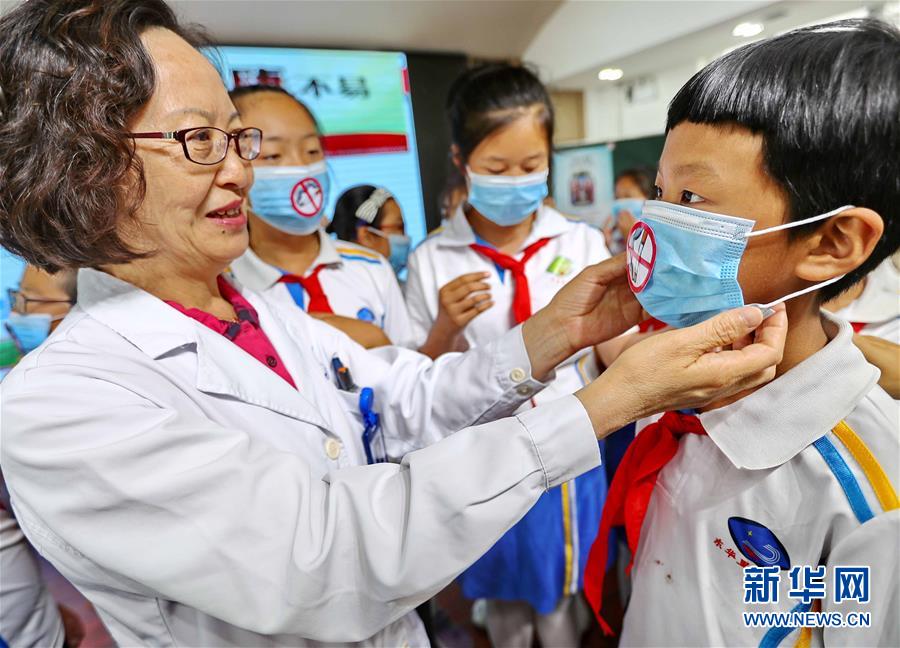 5月30日，秦皇岛市第一医院医务工作者为东华里小学学生佩戴禁烟标识口罩。