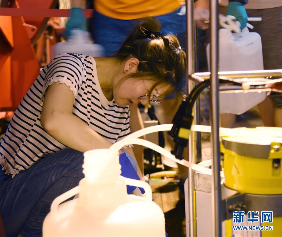 一名科考队员从“科学”号的温盐深仪采水瓶上取水样。