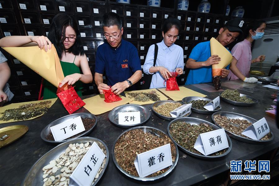 6月5日，中外留学生们在张同泰国药馆工作人员的指导下体验传统端午香包的制作。