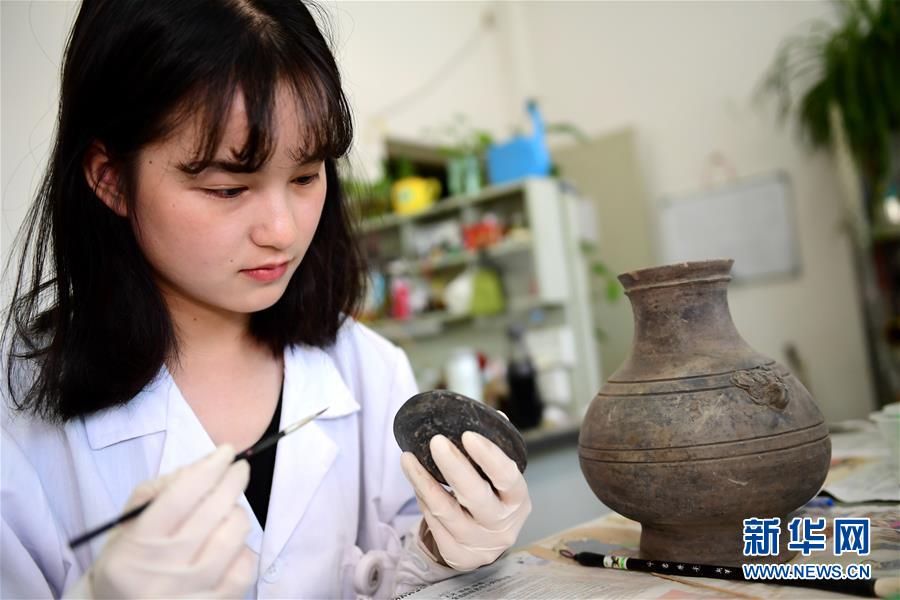 在洛阳市文物考古研究院，西北大学文物保护技术专业学生刘珈如在修复一件陶罐。