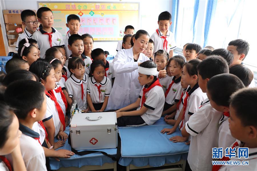 6月27日，在山东省滨州市博兴县第一小学，学校医务人员指导小学生学习急救包扎知识。