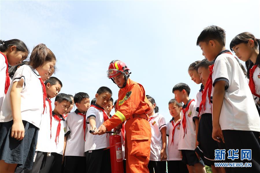 6月27日，在山东省滨州市博兴县第一小学，消防队员指导小学生学习使用灭火器。