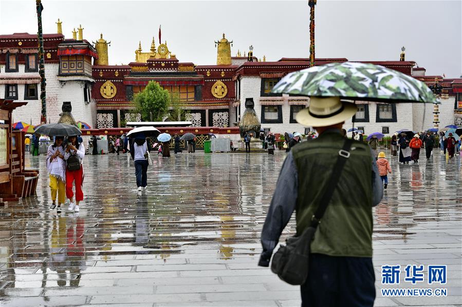 7月3日，人们在雨中游览大昭寺。