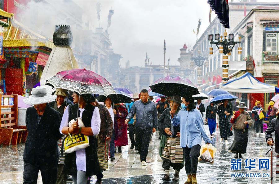 7月3日，八廓街上的人们在雨中漫步。