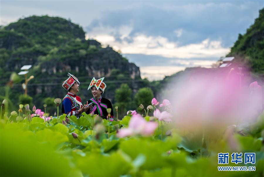 壮族姑娘彭绍英、钱星美（左）身着民族服饰在普者黑国家湿地公园游玩。
