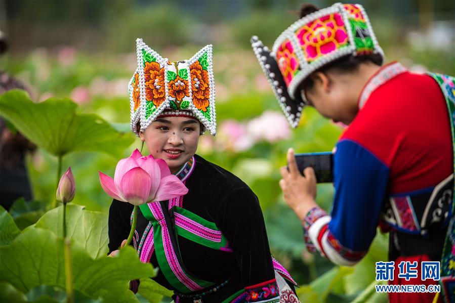 壮族姑娘彭绍英（左）身着民族服饰在普者黑国家湿地公园的荷花间留影。