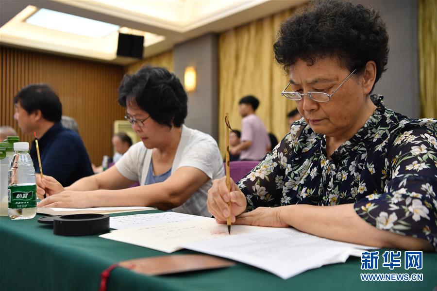 7月16日，陕西师范大学退休教师王书欣（右一）在书写录取通知书。