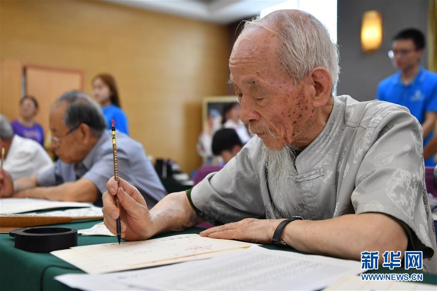 7月16日，陕西师范大学退休教师毋耀辉（前右一）在书写录取通知书。