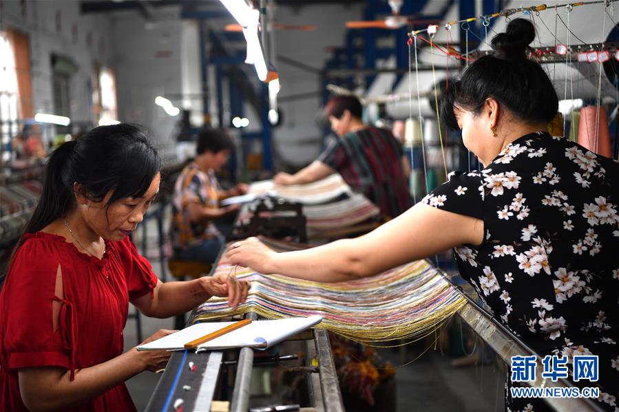 南阳宇翔工艺品有限公司的员工在车间编织真丝地毯。