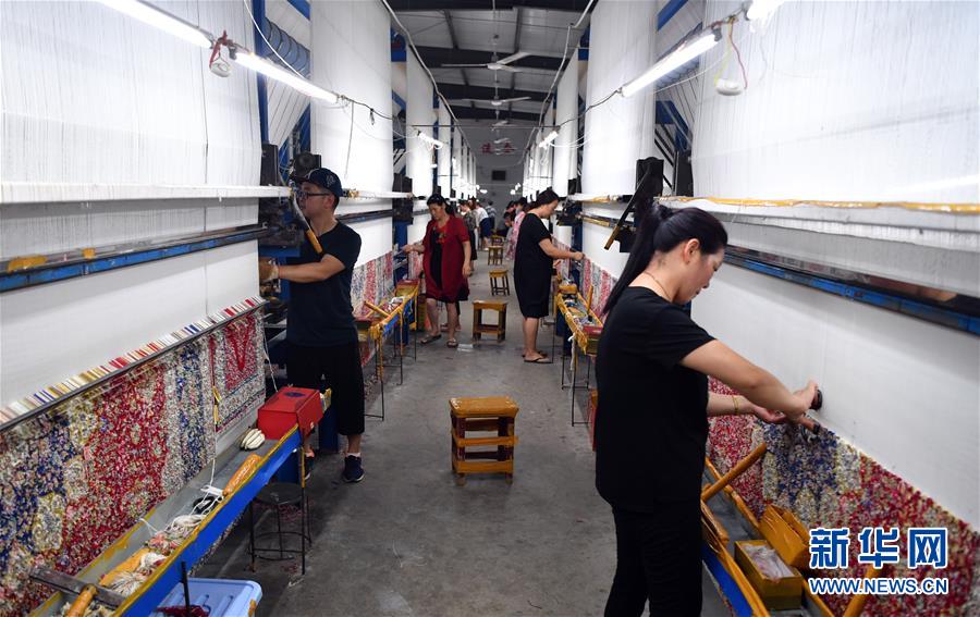 南阳宇翔工艺品有限公司的员工在车间编织真丝地毯。