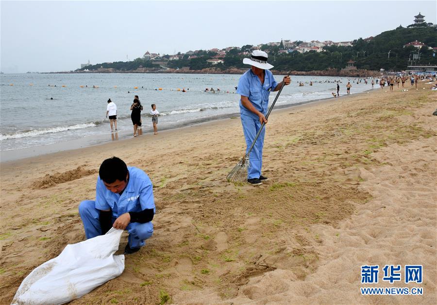 7月17日，保洁人员在青岛第一海水浴场清理海滩上残留的浒苔。