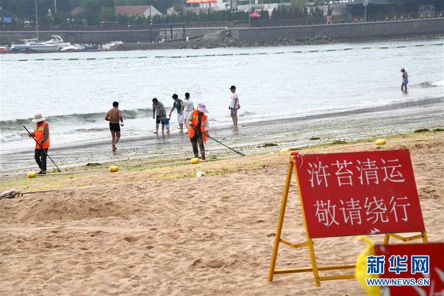7月17日，保洁人员在青岛第三海水浴场清理海滩上残留的浒苔。