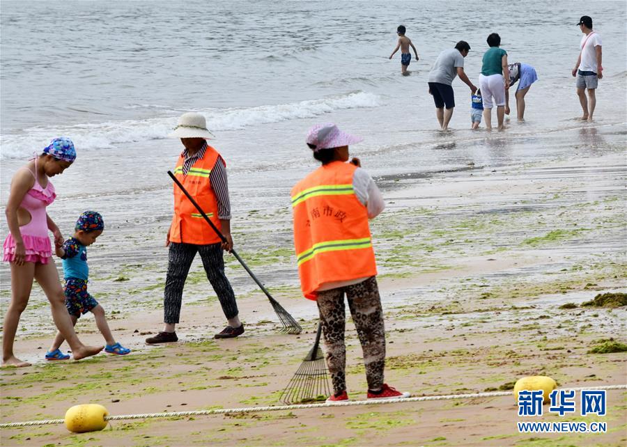 7月17日，保洁人员在青岛第三海水浴场清理海滩上残留的浒苔。