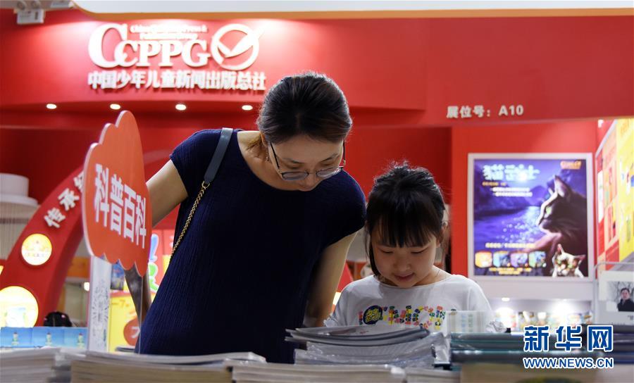 7月17日，一位小朋友在童书博览会上翻阅图书。