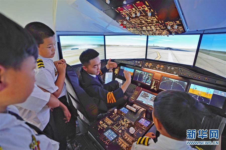 7月17日，夏令营教员（右二）向学员讲解C919模拟机驾驶知识。