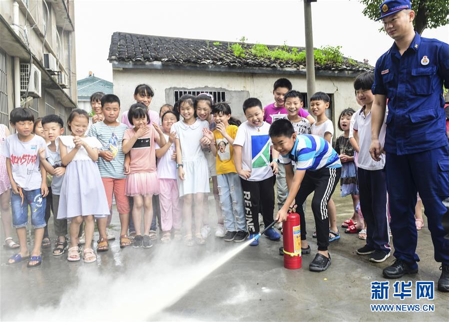 7月19日，小朋友在消防员的指导下学习使用灭火器。