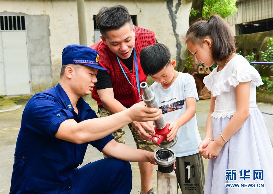 7月19日，小朋友在消防员的指导下体验消防救援器材。