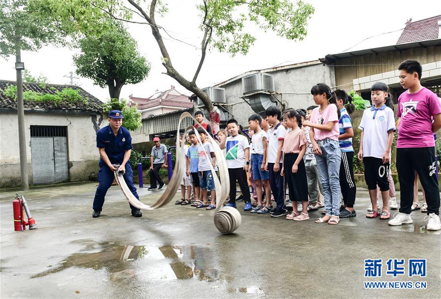 7月19日，消防员给小朋友们讲解消防器材的使用方法。